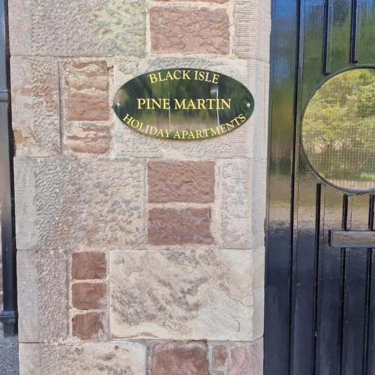 a sign on the door of a brick wall at Black Isle Holiday Apartments in Avoch
