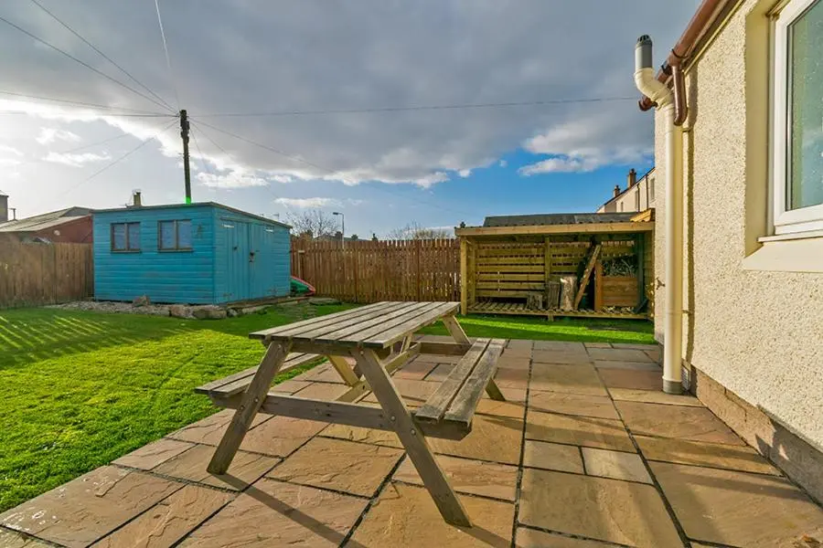 a wooden picnic table in the backyard of a house at Cosy Cottage Close to East Beach, Shops, Restaurants and RAF base in Lossiemouth