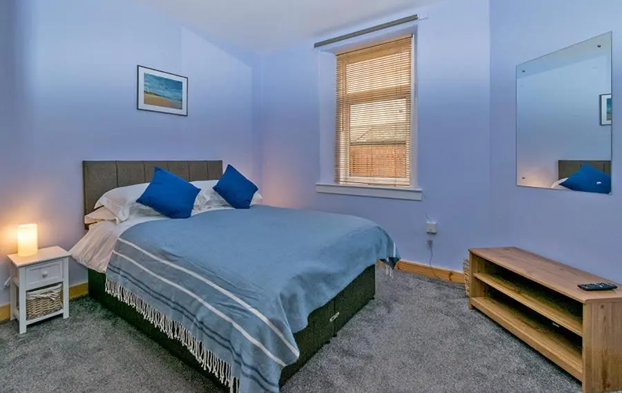 a bedroom with a bed with blue sheets and a window at Cosy Cottage Close to East Beach, Shops, Restaurants and RAF base in Lossiemouth