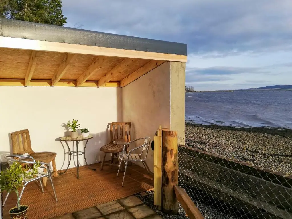 a patio with a table and chairs on the beach at St Brighs in Dingwall