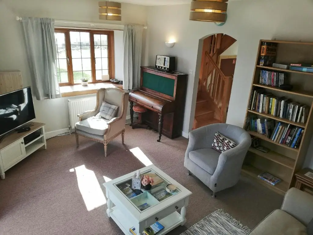 a living room with a piano and a chair at St Brighs in Dingwall