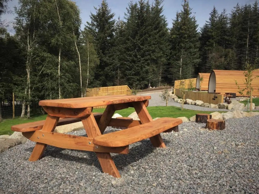 a wooden picnic table sitting on a pile of rocks at Tomatin Glamping Pods in Inverness