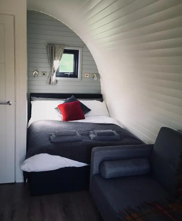 a bedroom with a bed with a red pillow and a couch at Tomatin Glamping Pods in Inverness