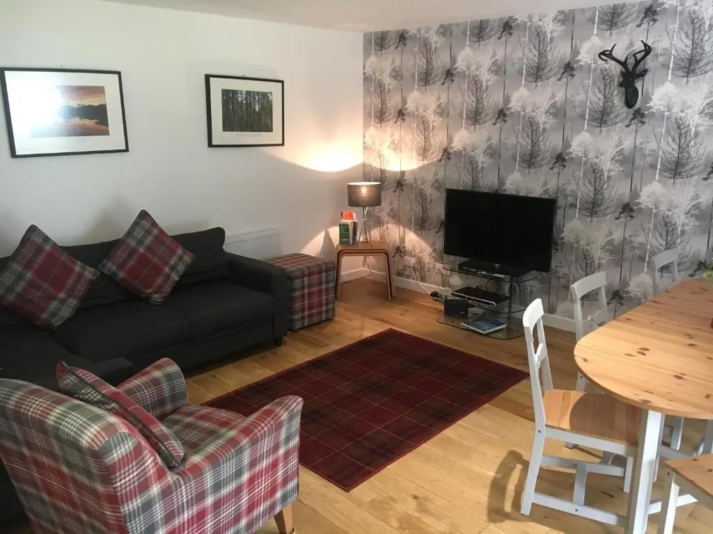 a living room with a couch and a table at 2 Dellmhor Cottages in Aviemore