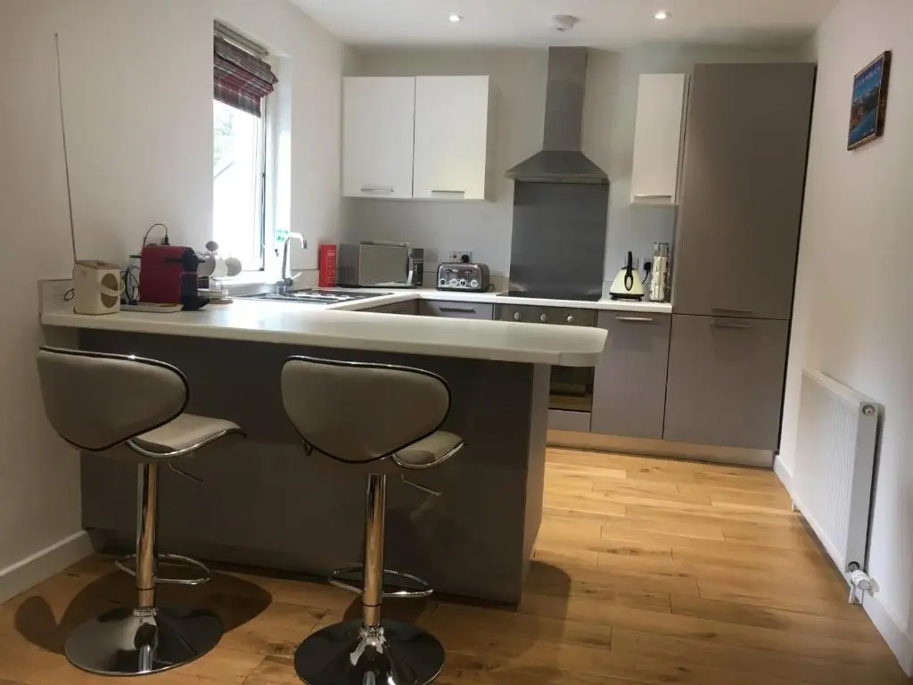 a kitchen with a counter and two bar stools at 2 Dellmhor Cottages in Aviemore