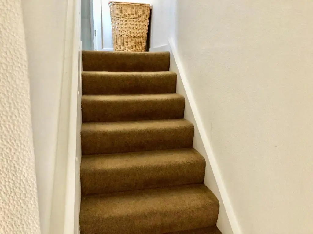 a staircase with brown carpet and a basket on the top at City Centre House in Inverness