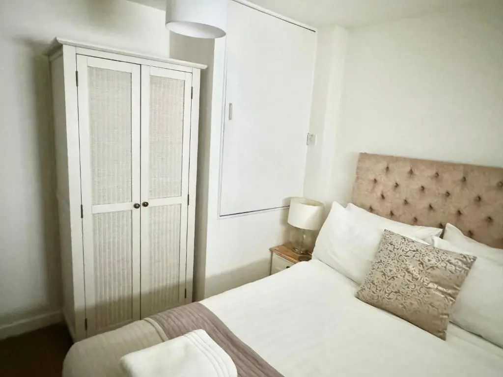 a bedroom with a white bed and a closet at City Centre House in Inverness