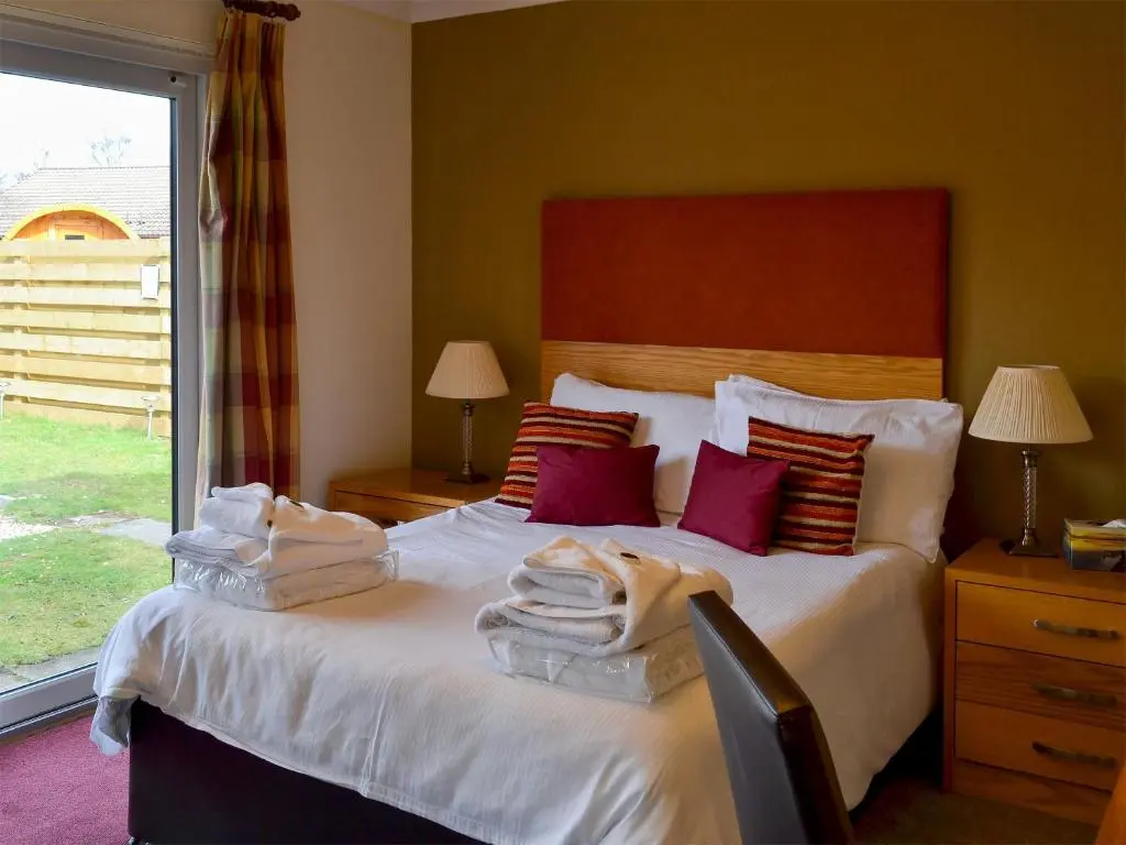 a bedroom with a bed with towels on it at Holly Lodge in Aviemore