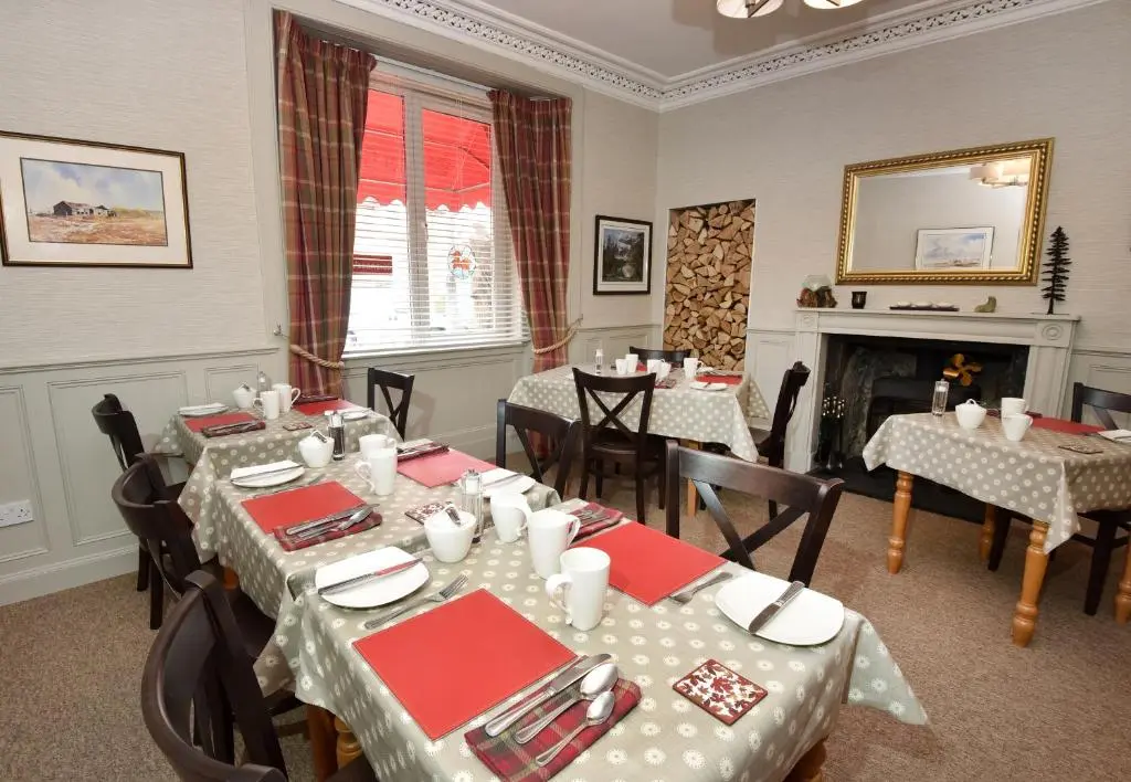 a dining room with tables and chairs and a fireplace at Acer Glen B&B in Inverness