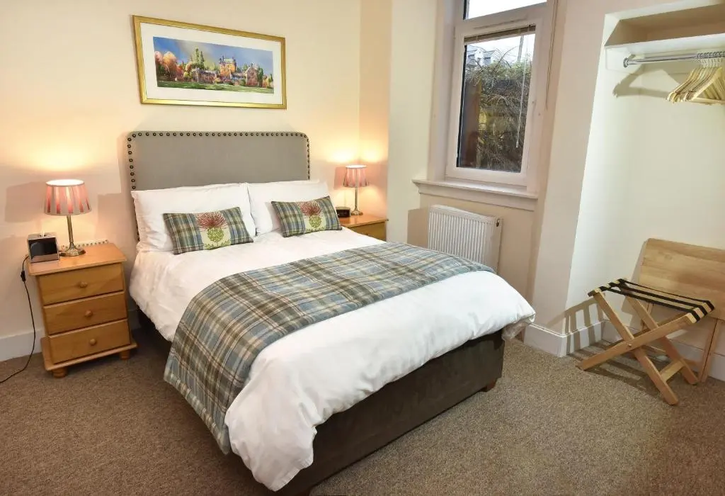a bedroom with a bed and two lamps and a window at Acer Glen B&B in Inverness