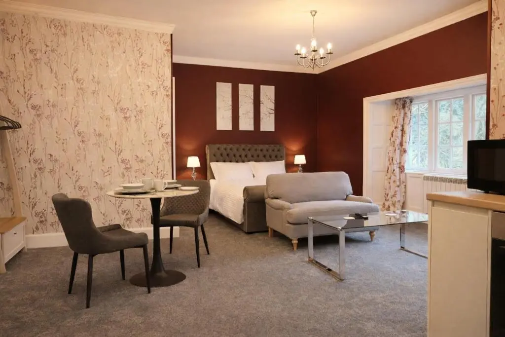 a hotel room with a bed and a table and chairs at Rossal House Apartments in Inverness