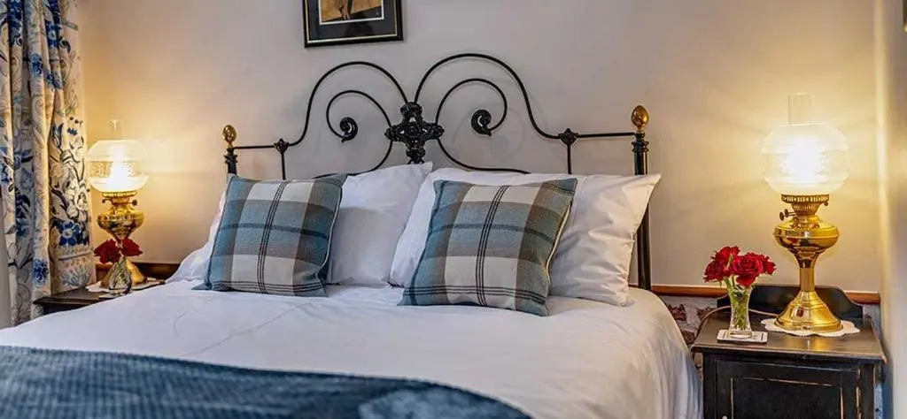 a bedroom with a bed with pillows and two lamps at Mill Of Nethermill Holidays in Pennan
