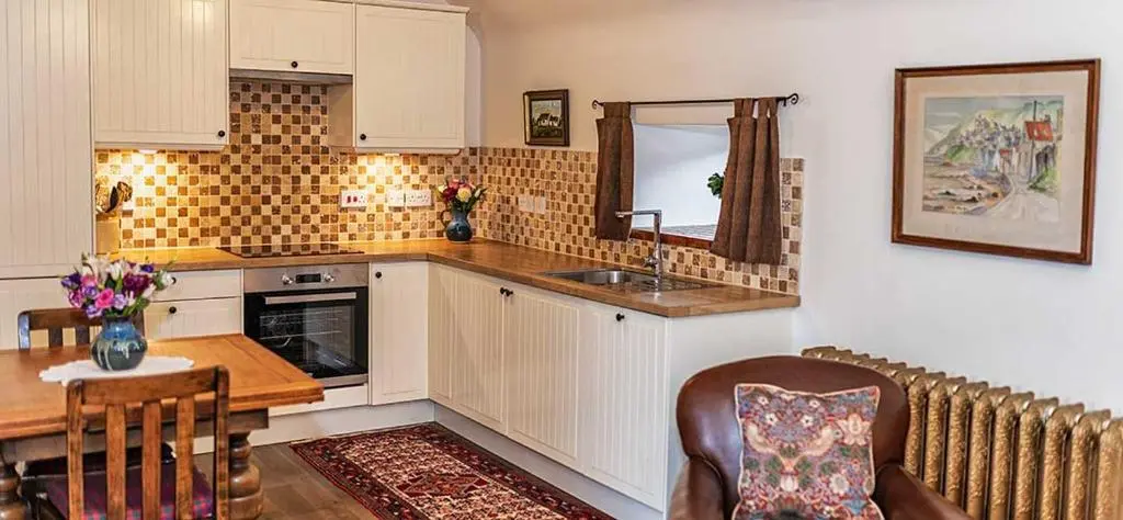 a kitchen with white cabinets and a table and a sink at Mill Of Nethermill Holidays in Pennan
