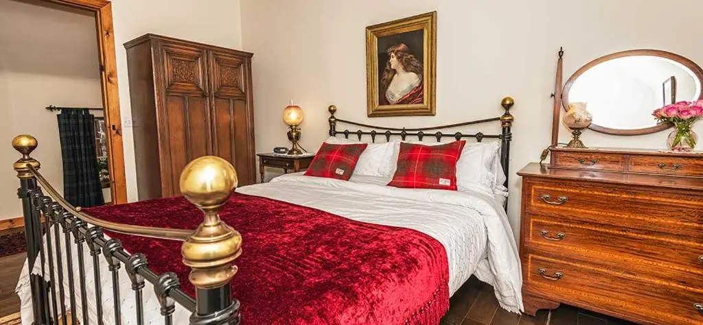 a bedroom with a bed and a dresser and a mirror at Mill Of Nethermill Holidays in Pennan
