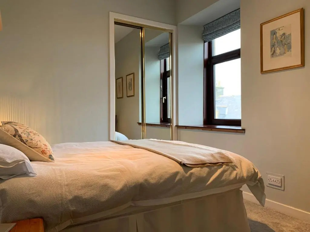 a bedroom with a bed with a large mirror at Hayfield Apartment in Lossiemouth