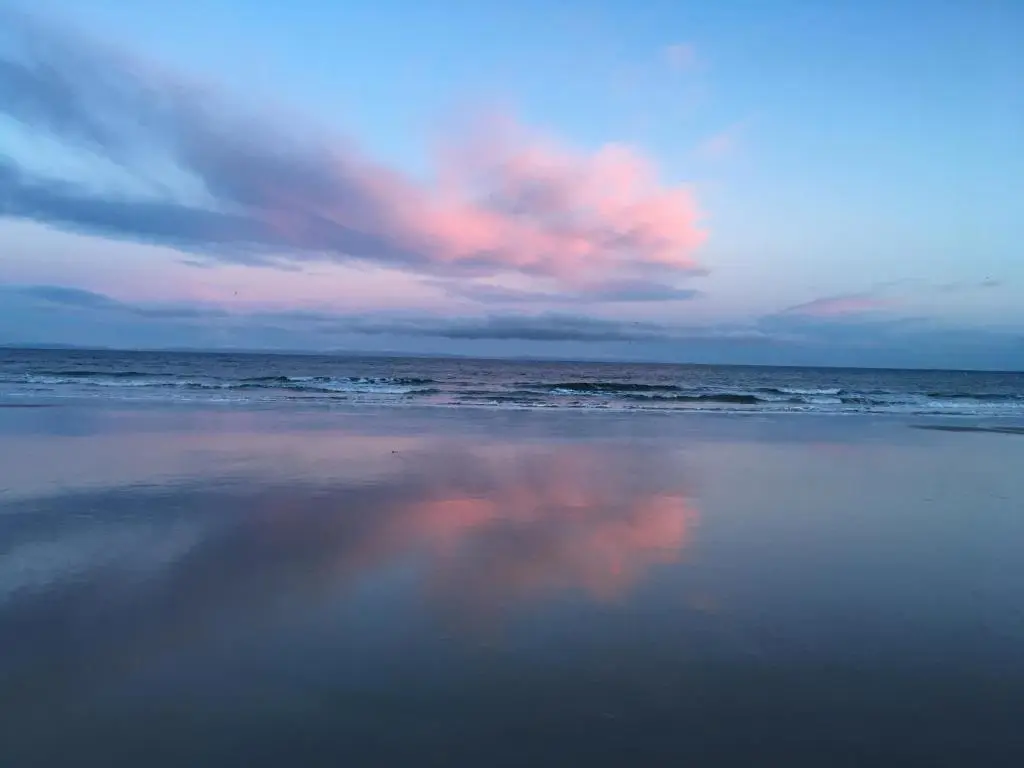a beach with a cloudy sky and the ocean at Hayfield Apartment in Lossiemouth