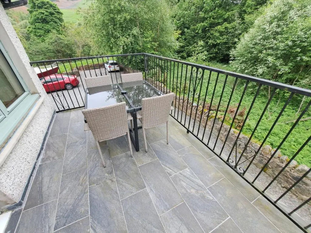 a patio with a table and chairs on a balcony at Loch Ness Balcony Apartment in Drumnadrochit