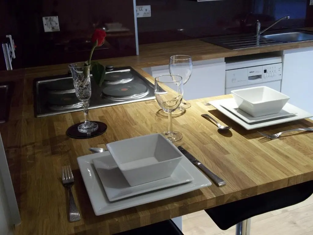 a table with a white plate and glasses on it at The Wee Thistle Loch Ness in Drumnadrochit