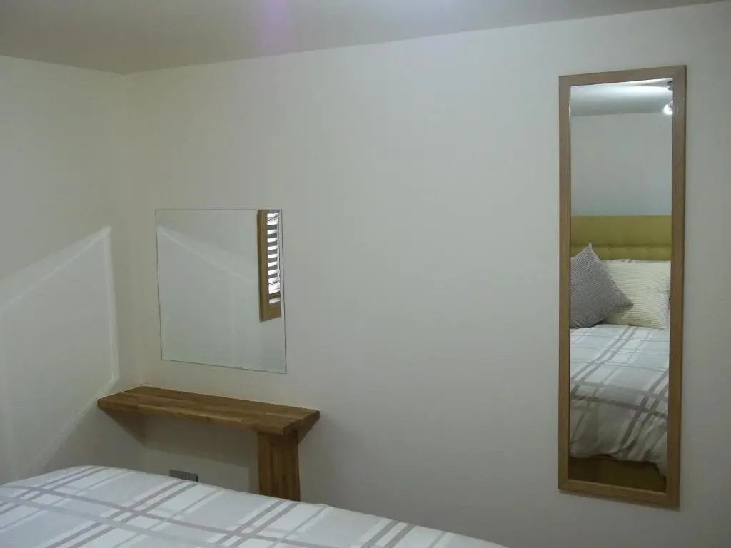 a bedroom with a mirror and a bed at The Wee Thistle Loch Ness in Drumnadrochit