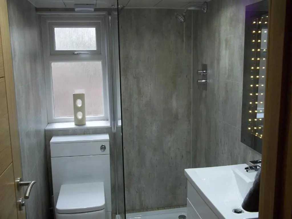 a bathroom with a shower and a toilet and a window at The Wee Thistle Loch Ness in Drumnadrochit