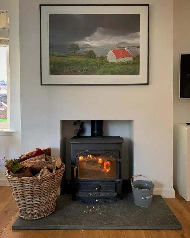 a stove in a living room with a picture on the wall at The Salmon Hut in Aberlour