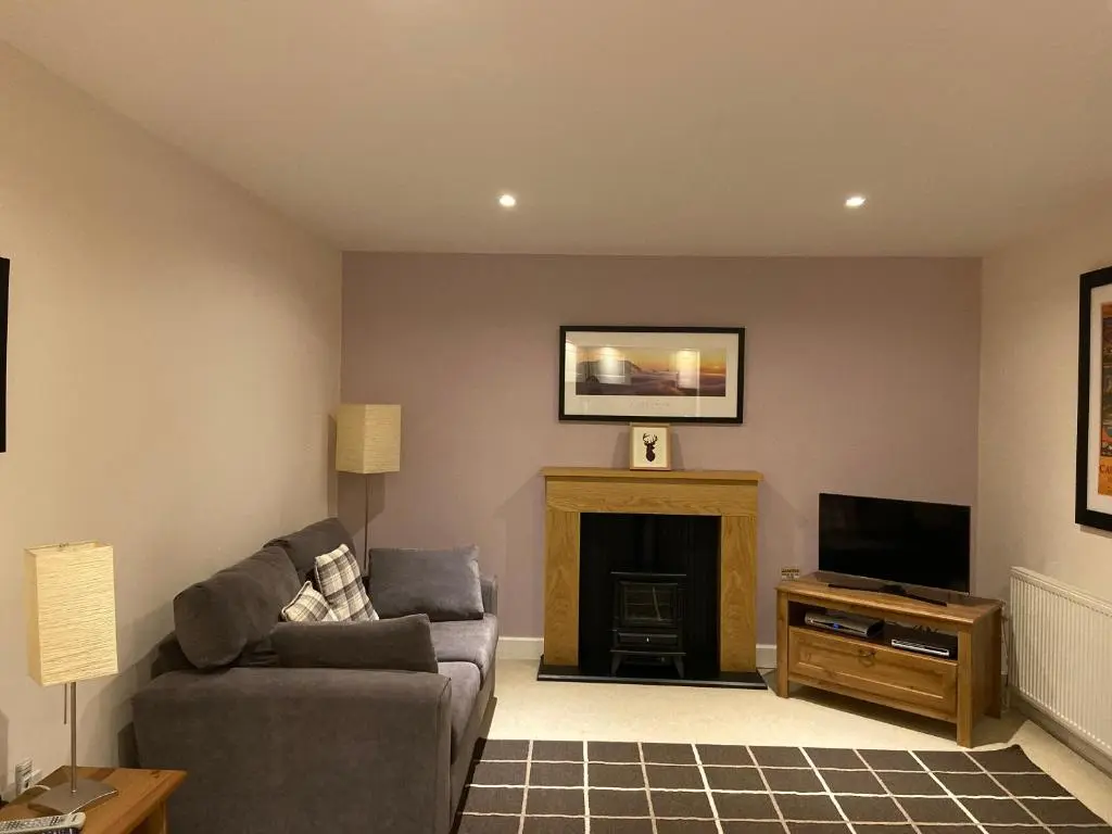 a living room with a couch and a fireplace at One Bedroom Apartment Highland Club Scotland in Fort Augustus