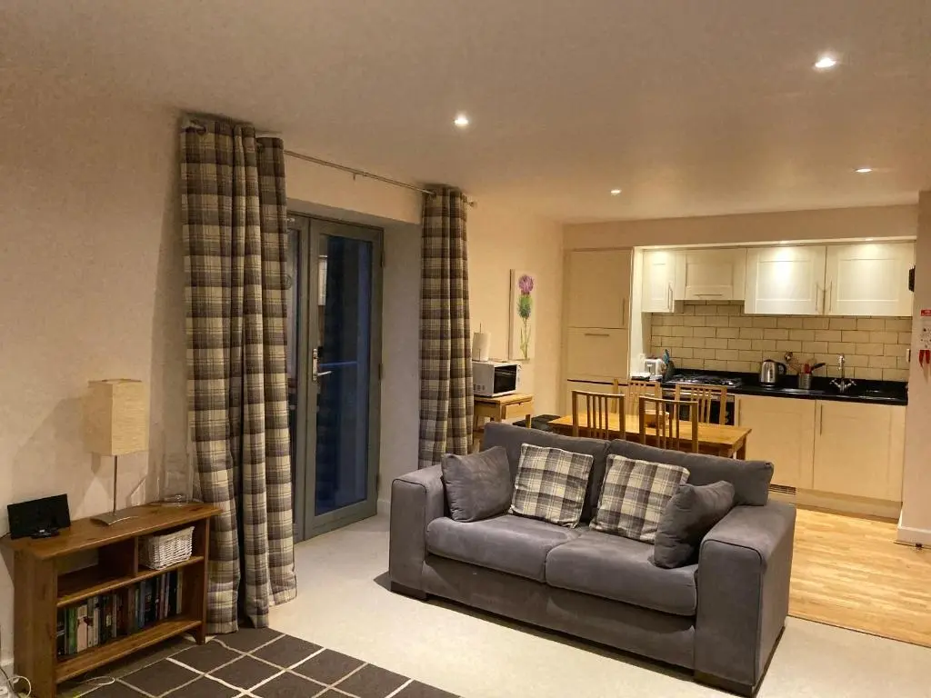 a living room with a couch and a kitchen at One Bedroom Apartment Highland Club Scotland in Fort Augustus