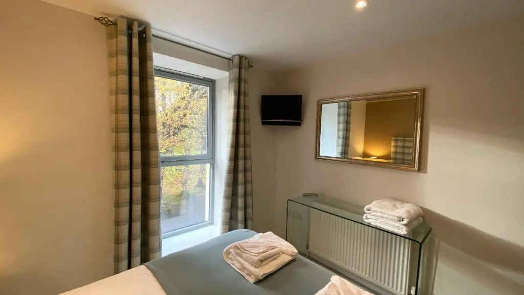 a bedroom with a bed and a mirror and a window at One Bedroom Apartment Highland Club Scotland in Fort Augustus