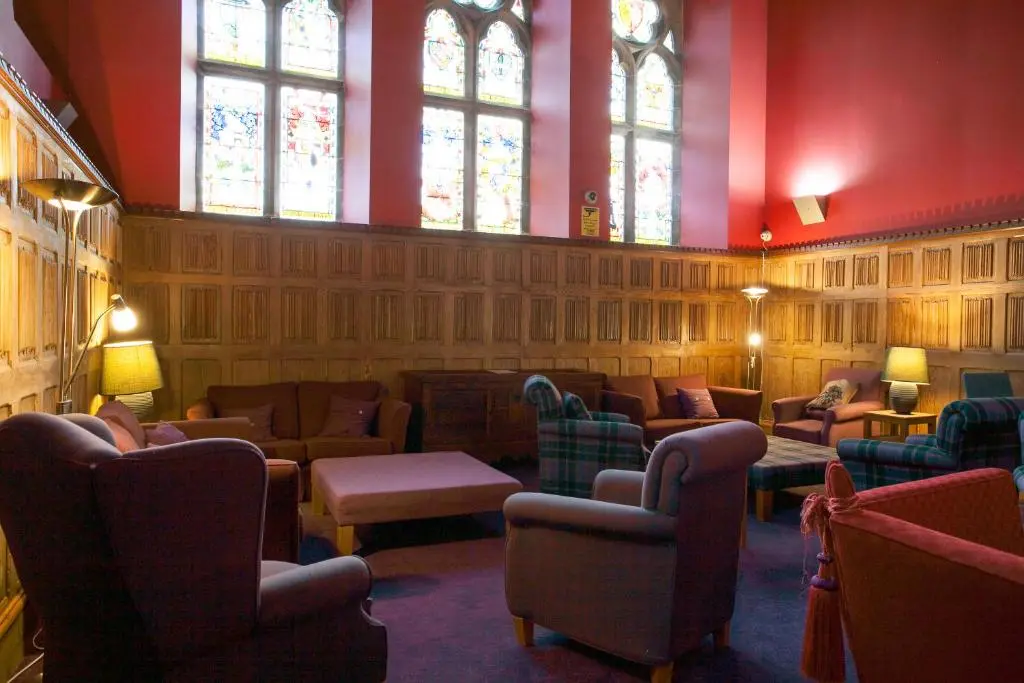 a waiting room with chairs and tables and stained glass windows at One Bedroom Apartment Highland Club Scotland in Fort Augustus