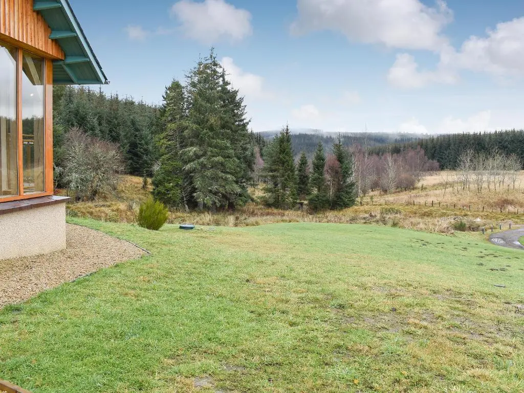 a large grassy yard with trees in the background at Mill Of Burncrook in Glenlivet