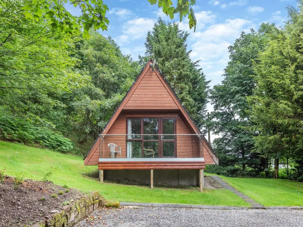 a small house with a window in the grass at Gorse Lodge - Uk7050 in Glenurguhart