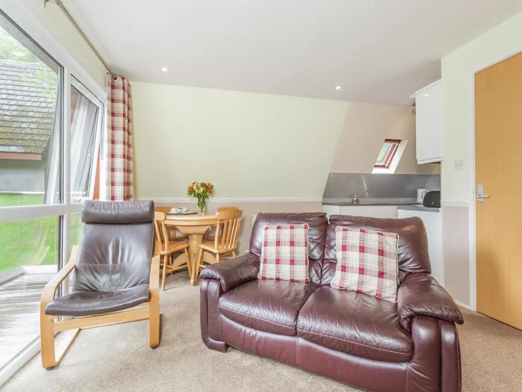 a living room with a leather couch and a table at Gorse Lodge - Uk7050 in Glenurguhart