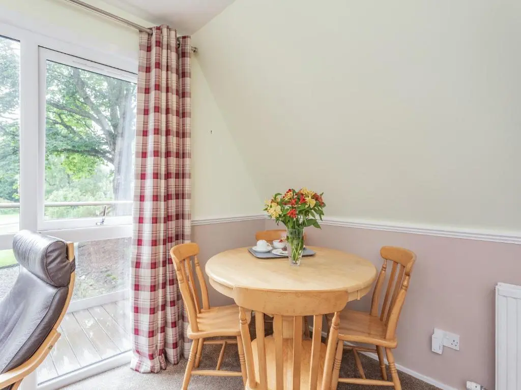 a dining room with a table and chairs and a window at Gorse Lodge - Uk7050 in Glenurguhart