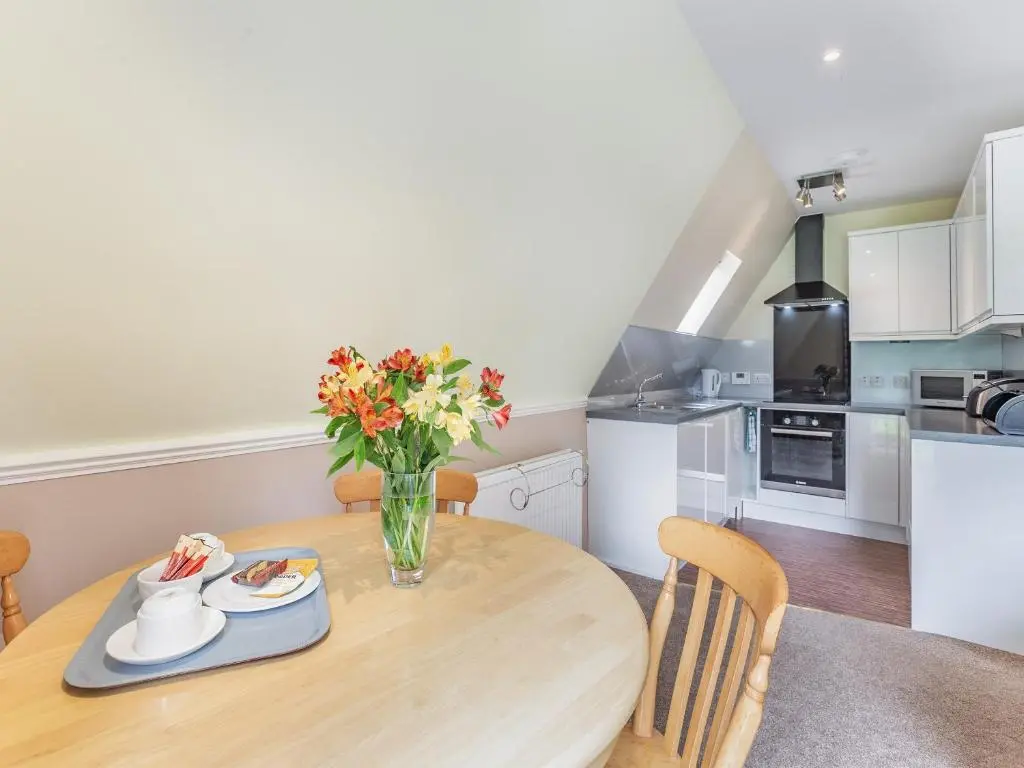a kitchen with a wooden table with a vase of flowers at Gorse Lodge - Uk7050 in Glenurguhart
