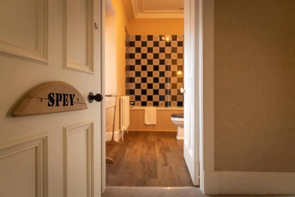 a bathroom with a toilet and a checkerboard wall at Craigellachie Lodge in Craigellachie