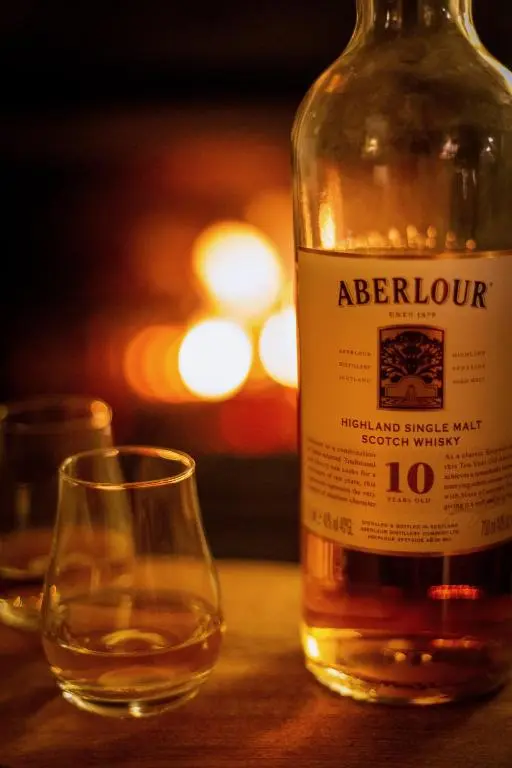 a bottle of alcohol sitting next to a glass at Craigellachie Lodge in Craigellachie