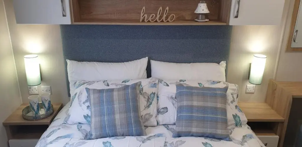 a bed with a blue headboard and two pillows at Bonnie Gorm in Boat of Garten