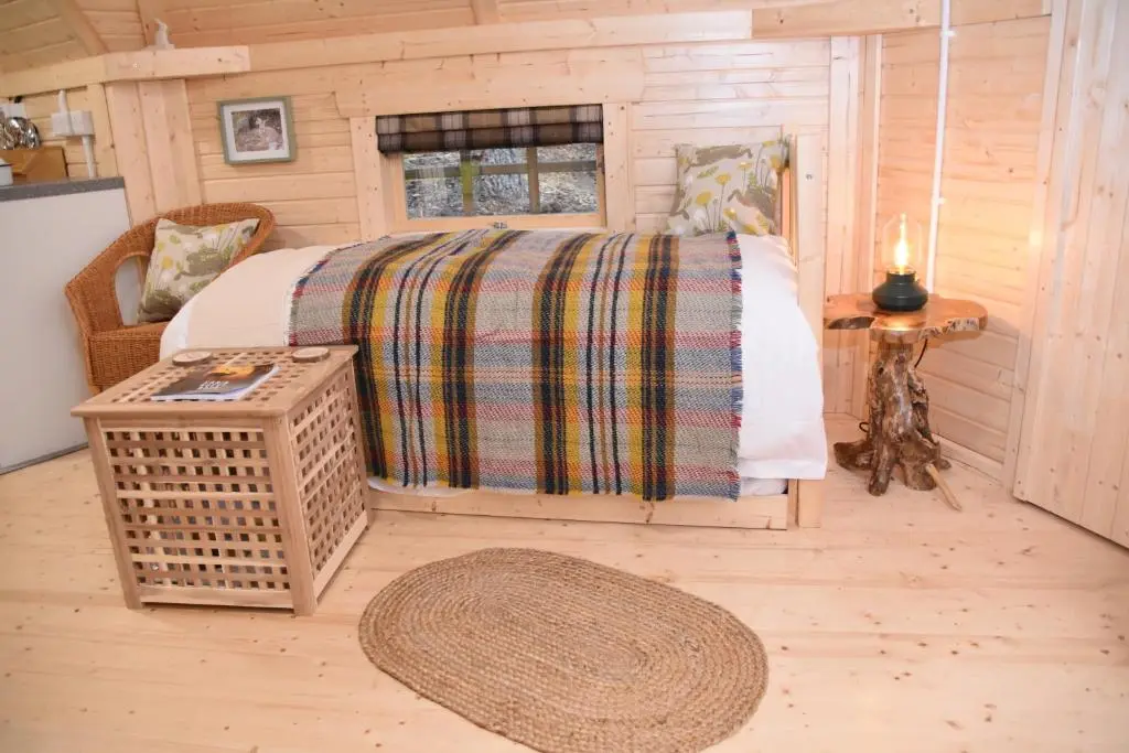 a bedroom with a bed in a log cabin at Cairngorm Bothies in Aboyne