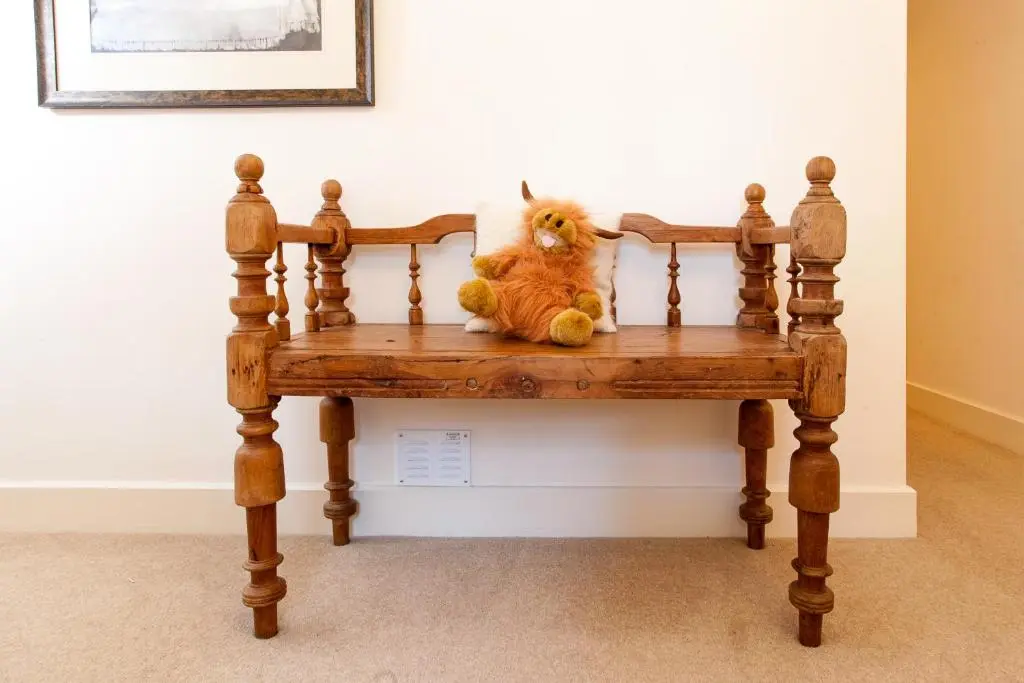 a small orange dog sitting on a wooden bench at Loch Ness Moat House Apartments in Fort Augustus