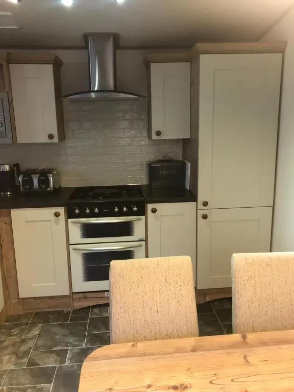 a kitchen with white cabinets and a stove top oven at 81 The Heathers, Aviemore Holiday Park , Dalfaber rd Aviemore PH22 1PX in Aviemore