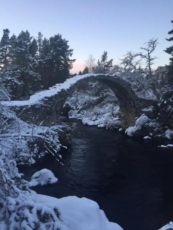 a bridge over a river covered in snow at 81 The Heathers, Aviemore Holiday Park , Dalfaber rd Aviemore PH22 1PX in Aviemore