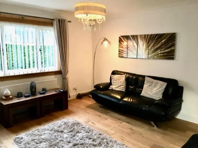 a living room with a black leather couch and a table at Culduthel Cottage in Inverness
