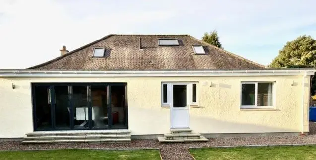 a white house with a large glass door at Culduthel Cottage in Inverness