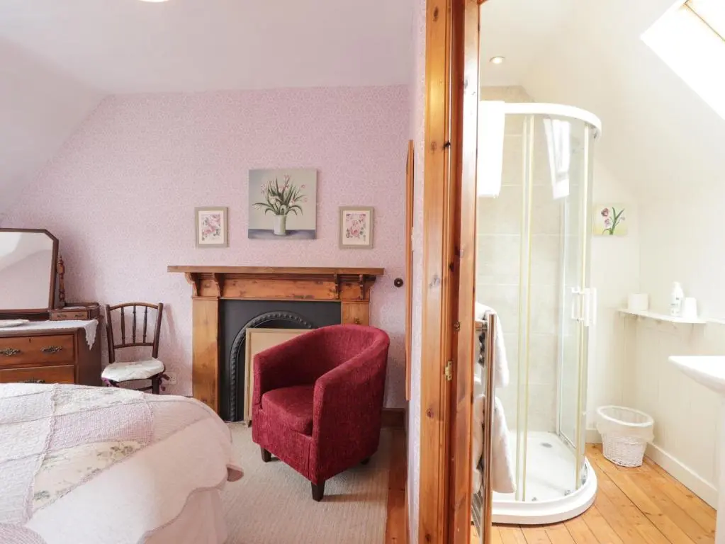 a bedroom with a bed and a chair and a fireplace at Glencanisp in Aviemore