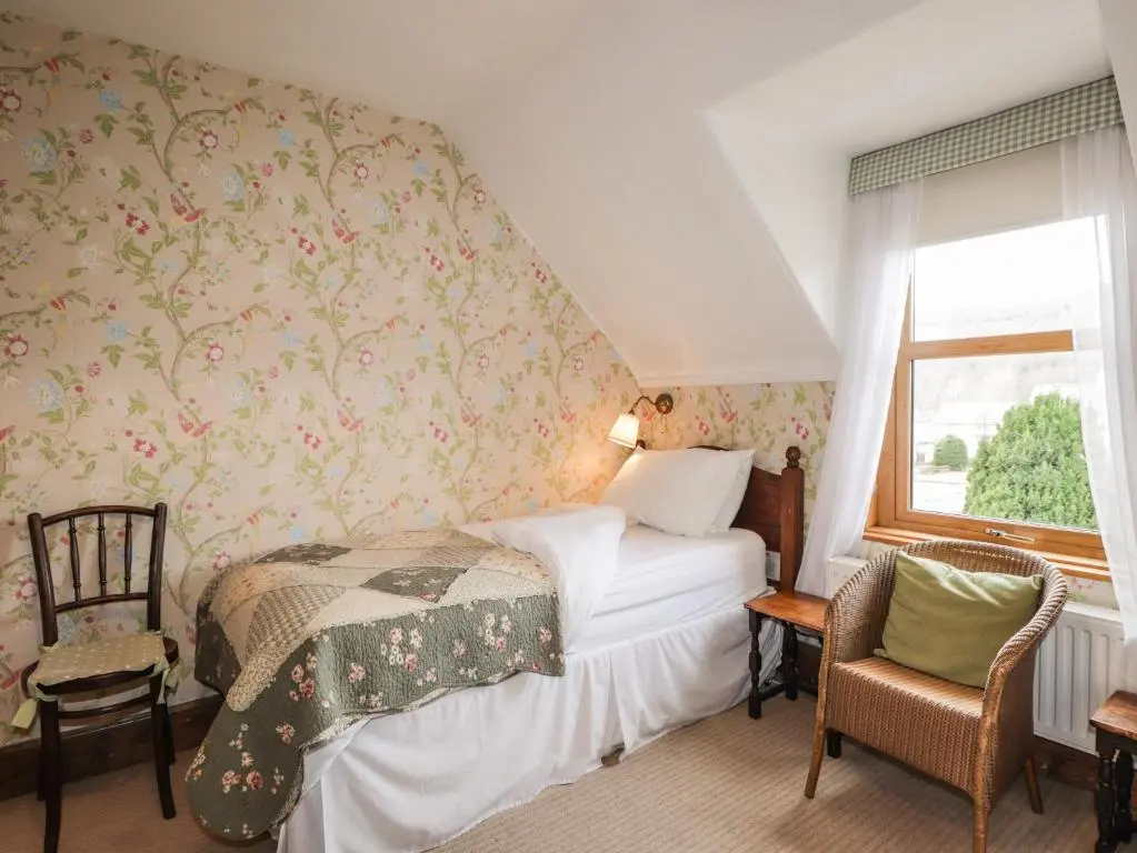 a bedroom with a bed and a window at Glencanisp in Aviemore