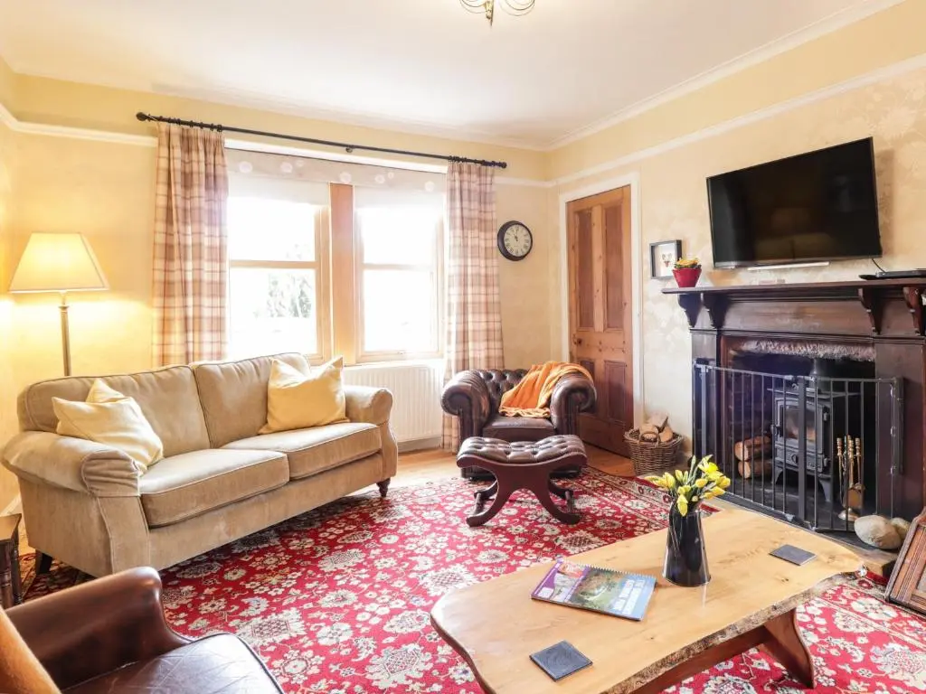 a living room with a couch and a fireplace at Glencanisp in Aviemore
