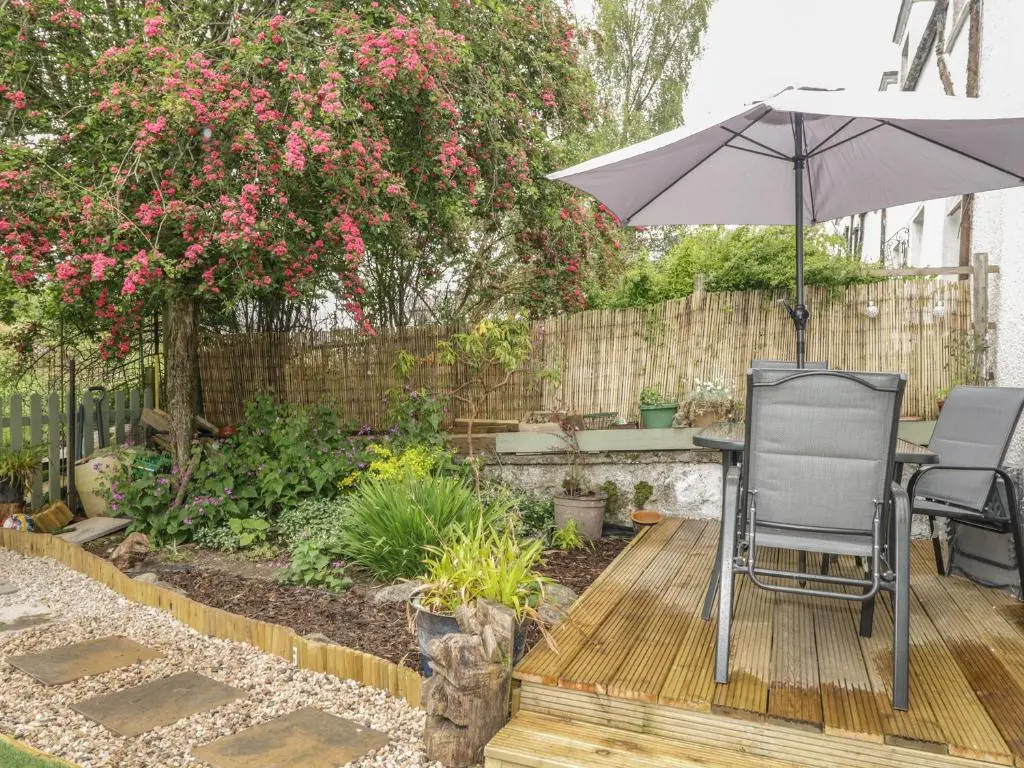 a patio with an umbrella and a table and chairs at Faodail Glenlia in Foyers