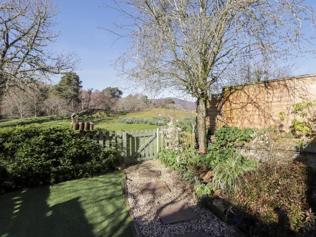 a garden with a fence and a tree at Faodail Glenlia in Foyers