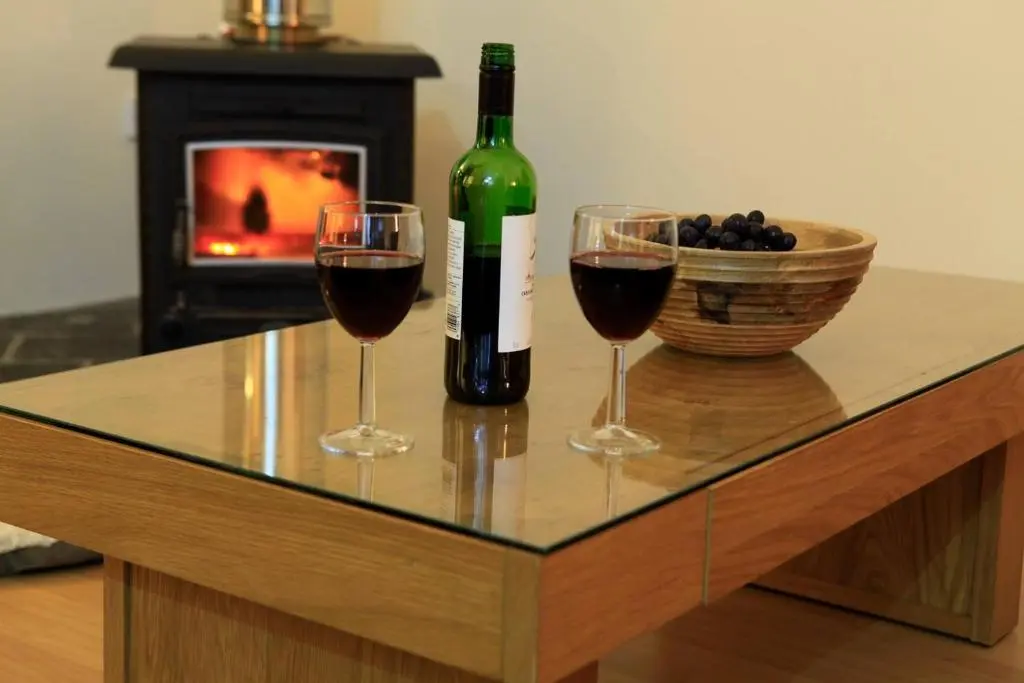 a bottle of wine and two wine glasses on a coffee table at Cairngorm Lodges in Aboyne