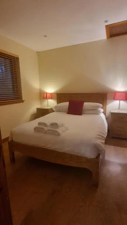 a bedroom with a large white bed with two lamps at Cairngorm Lodges in Aboyne